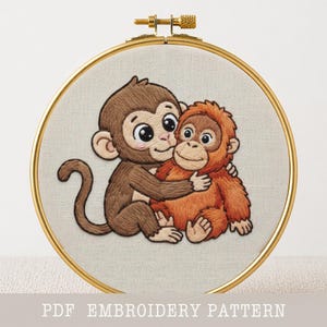 May include: Embroidered artwork featuring two cartoon monkeys hugging. One monkey is brown, the other is orange. The embroidery is set in a gold hoop. Text at the bottom reads "PDF EMBROIDERY PATTERN".