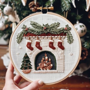 May include: Embroidered hoop art depicting a fireplace with stockings hung on the mantle and a small Christmas tree beside it. The fireplace is decorated with a garland of green leaves and red berries.
