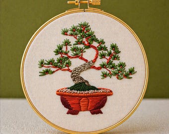 May include: Embroidered bonsai tree in a round gold hoop. The tree features green leaves, red accents, and a textured trunk, planted in a red-orange pot. The text "PDF EMBROIDERY PATTERN" is at the bottom.