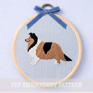 May include: An embroidered dog, likely a Collie, is displayed within a wooden embroidery hoop. The dog features brown, black, and white thread, set against a light blue striped fabric. A blue velvet ribbon and metal ring are at the top. The text "PDF EMBROIDERY PATTERN" is at the bottom.