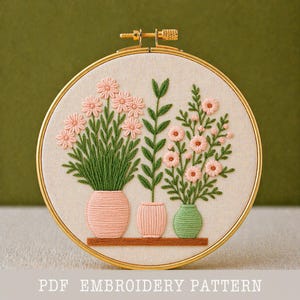 Könnte beinhalten: Gesticktes Blumendesign in einem goldenen Reifen. Das Kunstwerk zeigt drei Vasen mit rosa und grünen Blumen vor einem beigen Hintergrund. Der Text "PDF EMBROIDERY PATTERN" befindet sich unten.