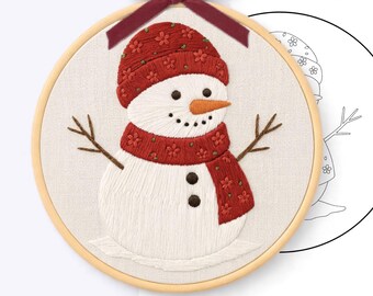 May include: A hand embroidery pattern featuring a snowman wearing a red hat and scarf with floral details, stitched in a 20 cm wooden hoop with a dark red velvet bow. The design includes brown stick arms, an orange nose, and black buttons.