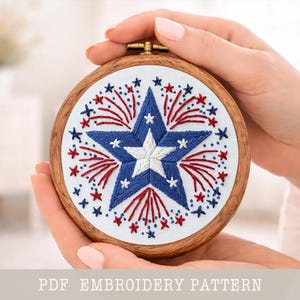 May include: Embroidered hoop art with a blue and white starburst design and red accents, set against a white background. The embroidery is framed in a round wooden hoop. Text at the bottom reads "PDF EMBROIDERY PATTERN".