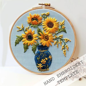 May include: Embroidery pattern template featuring a blue vase with yellow sunflowers and green leaves. The vase is decorated with a floral pattern. The template is for hand embroidery.