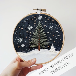 Könnte beinhalten: Eine Hand-Stickvorlage mit einer Tanne vor einem schneebedeckten Hintergrund und einem sternenklaren Nachthimmel. Die Vorlage befindet sich in einem runden Stickrahmen mit einem Holzrahmen.