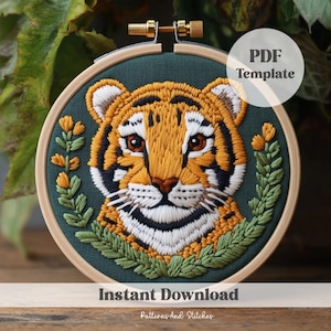 May include: A PDF template for embroidery featuring a cute tiger cub with green foliage around it. The design is on a dark green background. The text "PDF Template" and "Instant Download" are also included in the image.