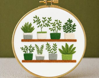 May include: Embroidered hoop art featuring a botanical design. The artwork showcases various green plants in pots, arranged on two wooden shelves. The embroidery is set within a gold-colored hoop. The text "PDF EMBROIDERY PATTERN" is at the bottom.