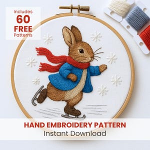 May include: Embroidery hoop featuring a charming embroidered design of a rabbit ice skating, wearing a blue jacket and red scarf. The design includes snowflakes and the text "Hand Embroidery Pattern Instant Download". Includes 60 free patterns.