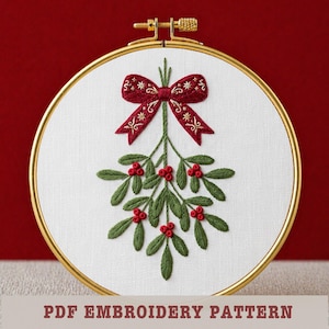May include: Embroidered mistletoe design in a gold hoop. The design features a burgundy bow with gold accents, green leaves, and red berries. The text "PDF EMBROIDERY PATTERN" is at the bottom.
