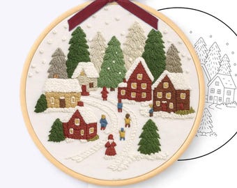 May include: A circular wooden embroidery hoop containing a winter village scene with red and tan houses, green pine trees, and snow-covered ground. A dark red velvet ribbon is tied at the top. Text reads: HAND EMBROIDERY PATTERN - PDF, HOOP 8 inch - 20 cm.