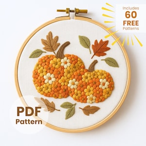 Może przedstawiać: Haft na tamborku przedstawiający dwie dynie wykonane z pomarańczowych i żółtych kwiatów, z brązowymi łodygami i zielonymi i pomarańczowymi liśćmi. Tekst "PDF Pattern" znajduje się w białym okręgu. Tekst "Includes 60 FREE Patterns" znajduje się w prawym górnym rogu.