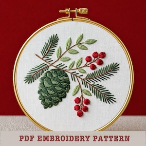 May include: Embroidered design featuring a green pinecone, evergreen branches, and red berries within a gold hoop. The embroidery is on white fabric. Text at the bottom reads "PDF EMBROIDERY PATTERN".