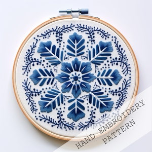 May include: Blue and white embroidery pattern in a wooden embroidery hoop. The pattern features a floral design with leaves and dots. The text "HAND EMBROIDERY PATTERN" is printed on the bottom right corner of the image.