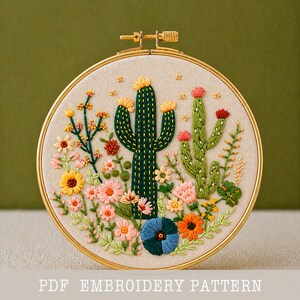 May include: A round embroidery hoop featuring a detailed cactus and floral design. The artwork includes a central green cactus with yellow accents, surrounded by colorful flowers in shades of pink, orange, and blue. The text "PDF EMBROIDERY PATTERN" is at the bottom.