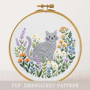 May include: A gray cat embroidery design in a gold hoop, surrounded by colorful flowers. The cat sits amidst lavender, daisies, and other blooms. The text "PDF EMBROIDERY PATTERN" is at the bottom.