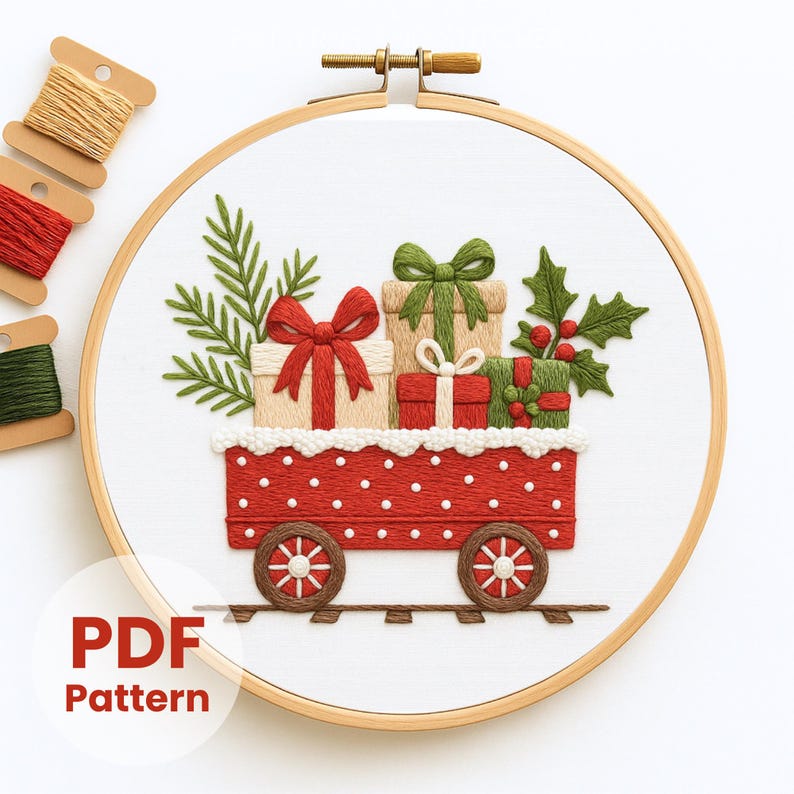 May include: Embroidered Christmas scene in a wooden hoop. A red train car with white polka dots carries wrapped gifts with green and red bows, holly, and pine branches. The text "PDF Pattern" is in the lower left corner. Spools of thread are in the upper left.
