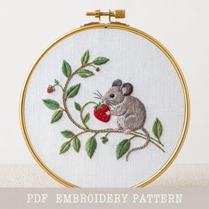 May include: Embroidered hoop art featuring a gray mouse perched on a branch, holding a red strawberry. The design includes green leaves and a gold-colored hoop. The text "PDF EMBROIDERY PATTERN" is at the bottom.