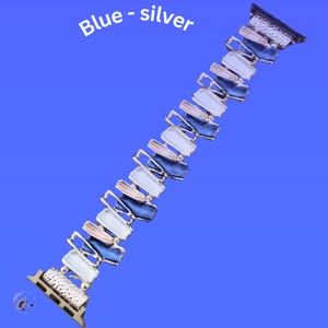 May include: A silver and blue Apple Watch band with a geometric design. The band is made of metal and has a gradient of blue, white, and pink colors.