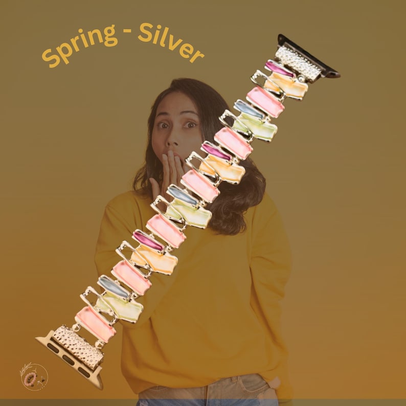 May include: A colorful, multi-colored, rectangular-shaped watch band with a silver finish. The band is made of a series of connected rectangular pieces, each with a different color. The band is designed for an Apple Watch.