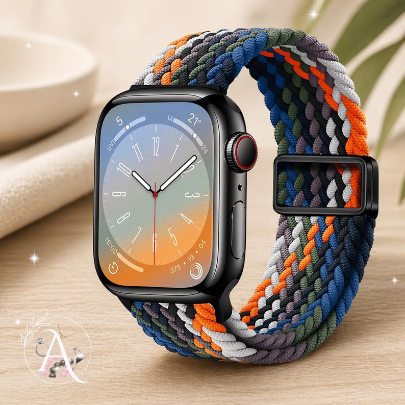 May include: A black smartwatch with a colorful braided band. The band features a mix of orange, blue, green, and gray strands. The watch face displays the time and other metrics. The watch is on a wooden surface.