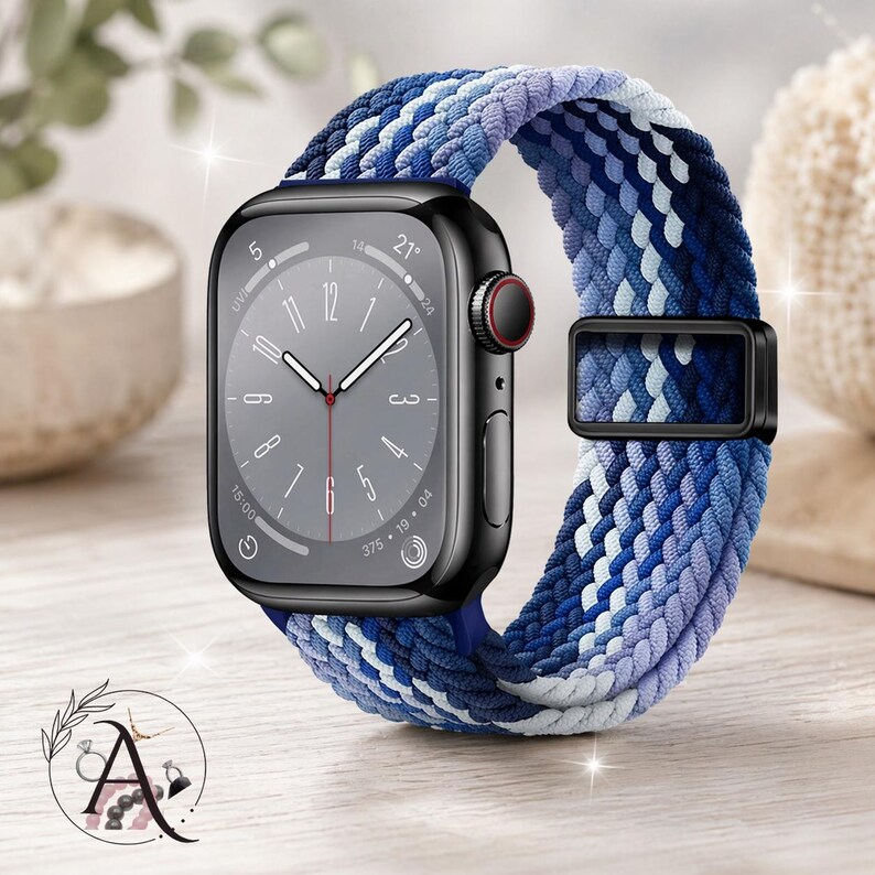 May include: A black smartwatch with a gray face and a braided watch band. The band features a mix of blue, white, and purple hues. The watch has a black buckle and a red dial. The watch is displayed on a wooden surface.