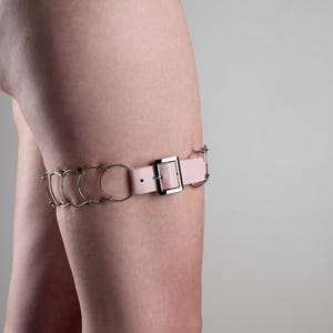 Cilicio de muslo, metal y cuero rosa, una hilera