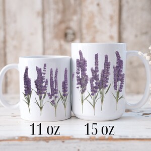 Op de afbeelding: Twee witte keramische mokken met lavendelbloemmotieven. De mok links is 11 ounce en de mok rechts is 15 ounce.