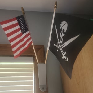 May include: Two flags hanging on a wall. The flag on the left is the American flag. The flag on the right is black with a white skull and crossbones.