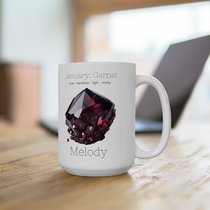 Peut inclure: Mug en céramique blanche avec une illustration d'une pierre précieuse de grenat rouge et le texte "Janvier : Grenat amour - amitié - lumière - vitalité Mélodie".