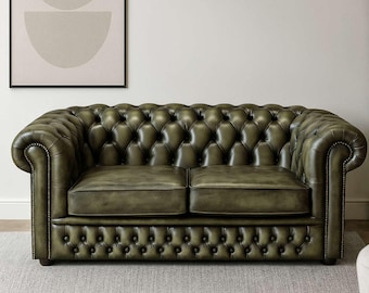 Sofá Chesterfield de dos plazas en piel verde oliva envejecida, hecho a mano en nuestro taller inglés. También se puede personalizar.