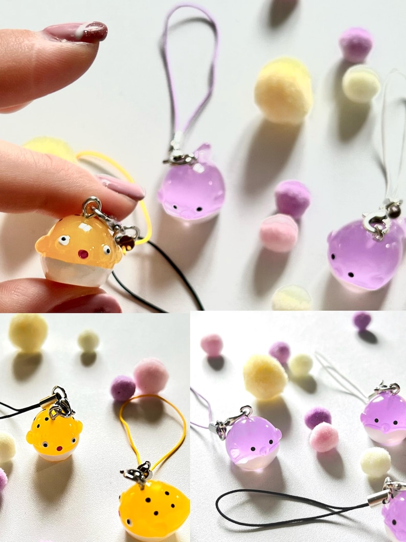 May include: A set of six colorful phone charms featuring a variety of designs, including pufferfish and whales. The charms are made of clear plastic and have a glossy finish. The charms are attached to colorful cords.