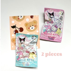 May include: Two packs of Hello Kitty erasers. One pack is pink with a Hello Kitty character and the other pack is blue with a Hello Kitty character. Both packs have a Hello Kitty logo and the text "Mini Erasers".