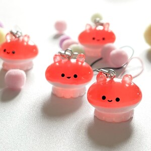 May include: Four pink and red jelly-like octopus charms with smiling faces. The charms are attached to silver chains and have a white base.