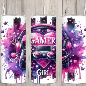 May include: A white tumbler with a Gamer Girl design. The design features a pink and purple watercolor background with a gaming controller, headphones, and the words "Gamer Girl". Hearts and stars are scattered around the design.
