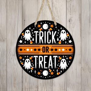 May include: A black and orange round Halloween door hanger with the text "Trick or Treat" surrounded by ghosts and candy corn.