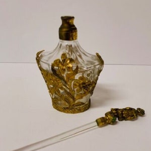 May include: A vintage glass perfume bottle with a gold floral design and a matching glass and gold dropper.