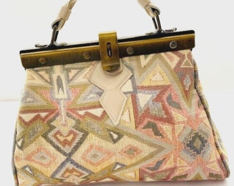 Cartera tejida con aspecto de tapicería en colores neutros con pies de monedero metálicos. hermosa vendimia