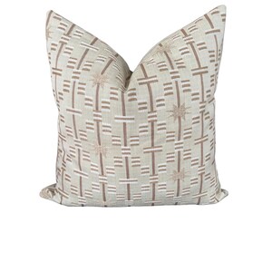 May include: A decorative square pillow with a geometric pattern. The pillow features a beige background with a repeating pattern of brown and white lines and starburst shapes. The pillow is a neutral color and would complement any home decor.