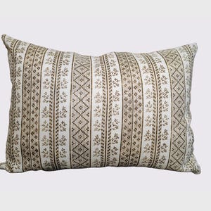 May include: Rectangular decorative pillow with a cream-colored background and a repeating pattern of vertical stripes in shades of brown. The stripes feature floral and geometric designs, creating a textured appearance. The pillow is designed for home decor.