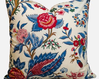 May include: A white pillow with a floral pattern in shades of blue, red, and pink. The flowers are stylized and have a vintage feel.