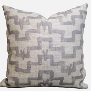 May include: A decorative throw pillow with a geometric pattern in shades of gray and white. The pillow is made of a soft, textured fabric.