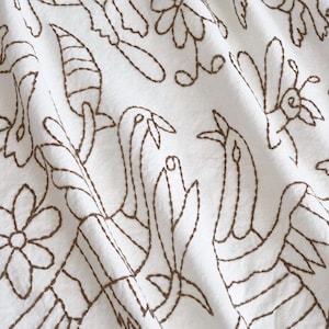 May include: White fabric with a brown embroidered design of stylized birds and flowers.