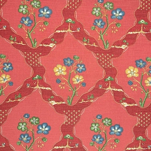 May include: A red fabric with a repeating pattern of blue, yellow, and green flowers. The flowers are arranged in a symmetrical pattern on a red background.