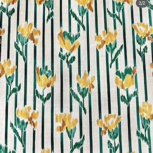 May include: White fabric with green stripes and a repeating pattern of yellow flowers. The flowers have a stylized, almost brushstroke-like appearance.