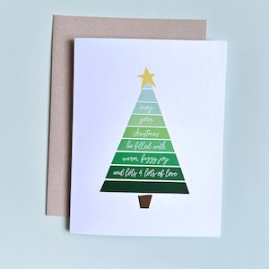 May include: A Christmas greeting card with a green tree design. The tree is composed of layered green shapes, topped with a yellow star, and includes the message "May your Christmas be filled with warm, fuzzy joy and lots & lots of love."