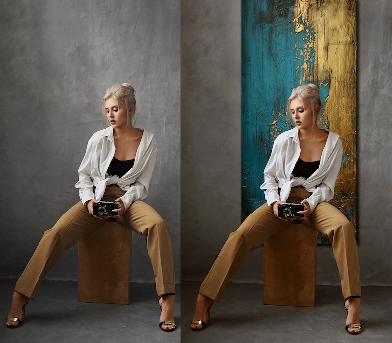 May include: A woman wearing a white shirt and brown pants sits on a stool in front of a blue and gold abstract painting. She is holding a vintage camera in her hands.