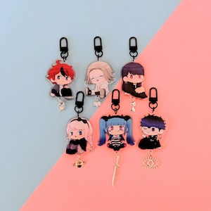 Puede incluir: Colección de siete llaveros de personajes de estilo anime. Cada llavero presenta un personaje diferente con cabello y ropa únicos, sujeto a un cierre negro. Algunos llaveros tienen pequeños amuletos, como una espada, un ojo y un planeta.