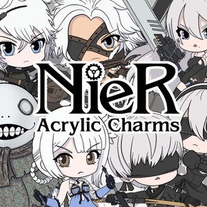May include: A set of Nier: Automata acrylic charms featuring characters from the video game. The characters are depicted in a chibi style and include 2B, 9S, A2, and Pod 153. The charms are black and white with some grey and brown accents. The text "Nier Acrylic Charms" is displayed in the center of the image.