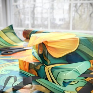 May include: Two rectangular boxes wrapped in glossy paper featuring a vibrant abstract pattern of swirling yellow, orange, and teal shapes. A roll of the same patterned wrapping paper and a pair of black scissors lie nearby on the surface.