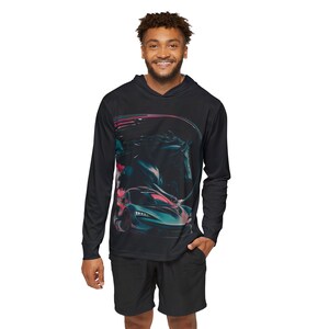 May include: Black long-sleeved hooded top featuring a teal and red sports car graphic. The top is worn with black shorts. The design includes a dark background with abstract shapes and lines.
